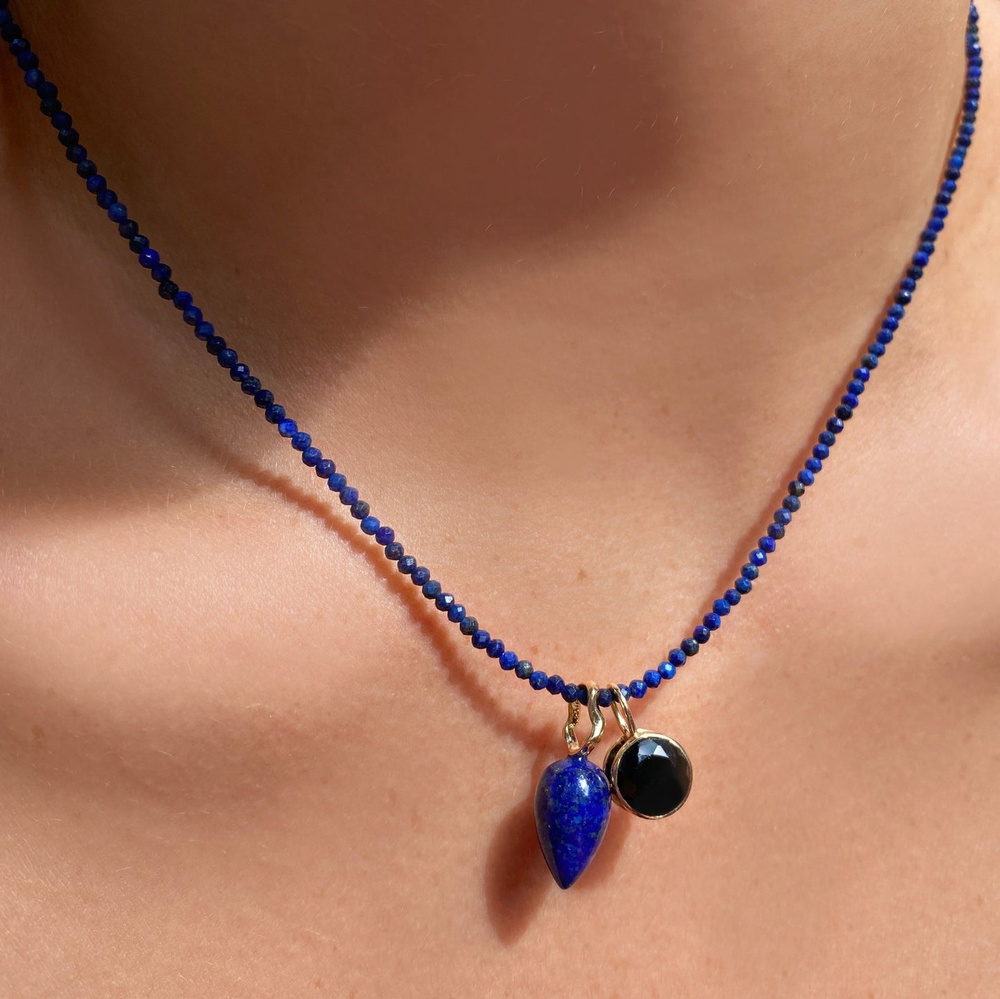 Lapis acorn drop charm. Styled on a neck with a rounded solitaire charm hanging from a beaded necklace.