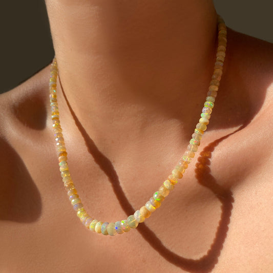 Shimmering beaded necklace made of faceted opals in shades of pastel yellow and clear opals on a gold linking ovals clasp.