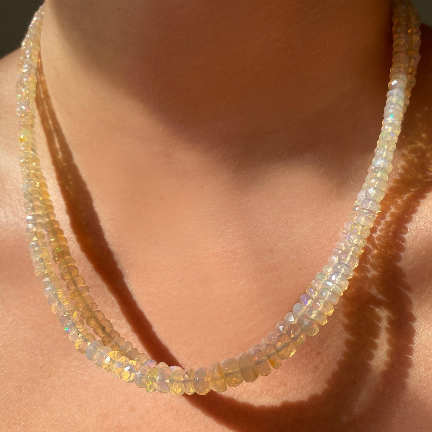 Shimmering beaded necklace made of faceted opals in shades of clear and nude opals on a gold linking ovals clasp.