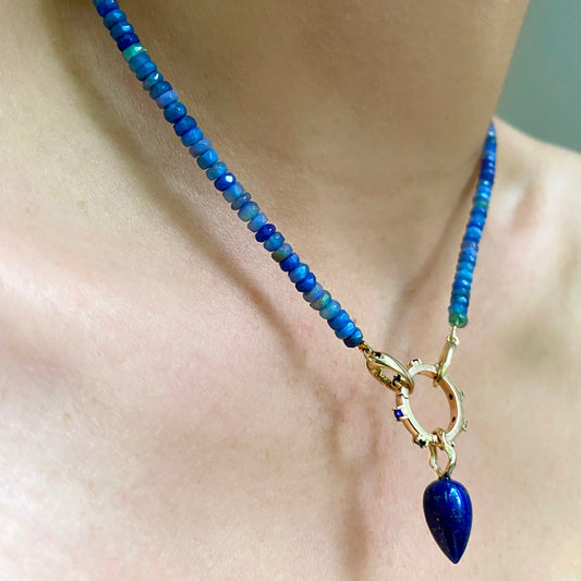 Lapis acorn drop charm. Styled on a neck hanging from a rounded charm lock and beaded necklace.