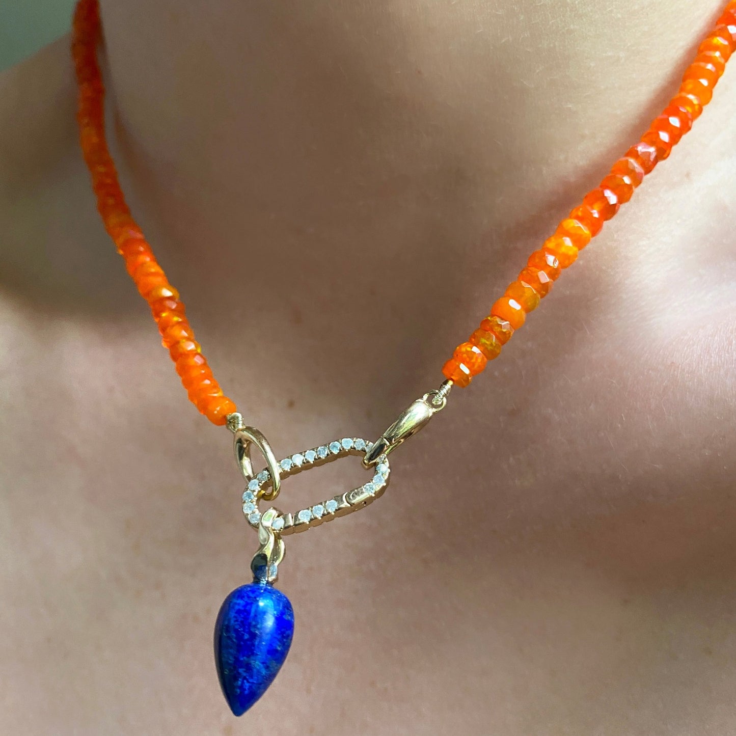 Lapis acorn drop charm. Styled on a neck hanging from a oval charm lock and beaded necklace.