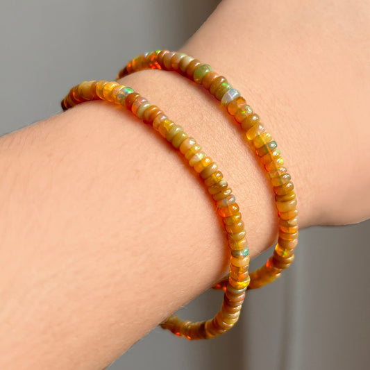 Shimmering beaded bracelet made of smooth opals in shades of light brown and light orange on a gold linking lobster clasp.