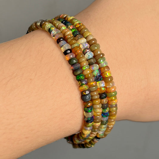 Shimmering beaded bracelet made of faceted opals in shades of green, yellow, brown, black, and clear on a gold linking lobster clasp.
