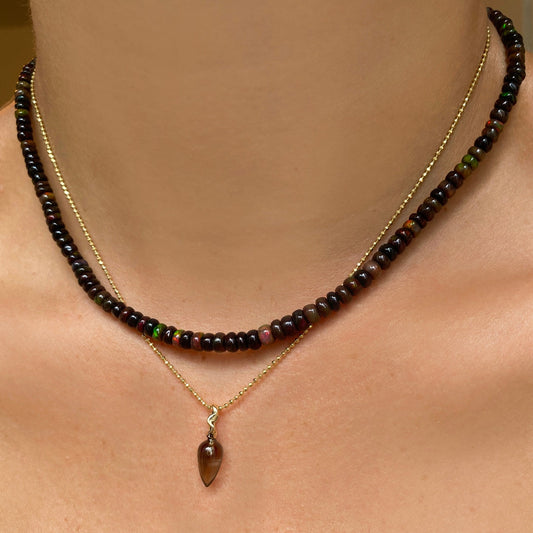Shimmering beaded necklace made of faceted opals in shades of brown on a gold linking ovals clasp. Styled on a neck layered with a bead chain necklace and acorn drop charm.