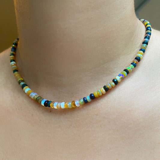 Shimmering beaded necklace made of faceted opals in shades of yellow, white, clear, brown, and black on a gold linking ovals clasp. 