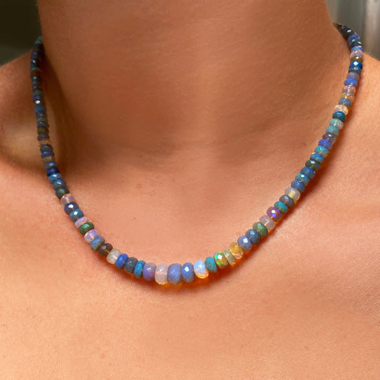 Shimmering beaded necklace made of faceted opals in shades of light blue, light purple, yellow, white, and clear on a gold linking ovals clasp.