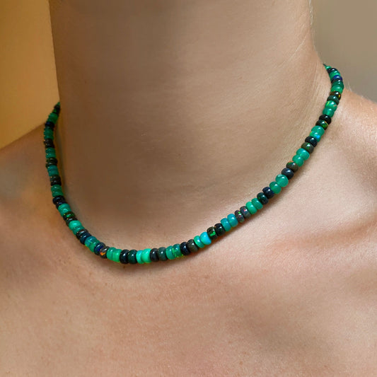 Shimmering beaded necklace made of smooth opal rondels in shades of green and black on a slim gold lobster clasp.