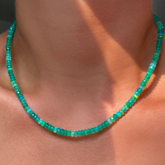 Shimmering beaded necklace made of faceted opals in shades of light green on a gold linking ovals clasp.