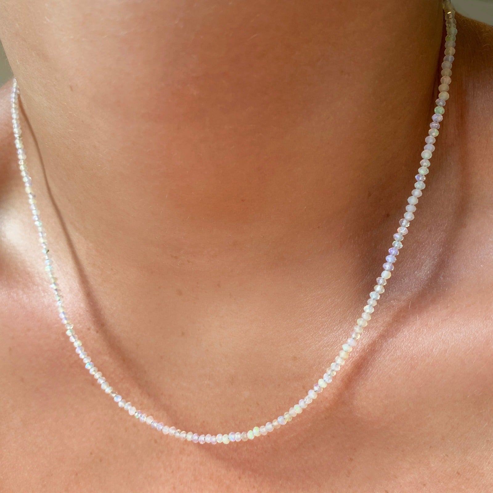 Shimmering beaded necklace made of 2.5mm faceted opals in shades of milky white on a gold linking lobster clasp. 