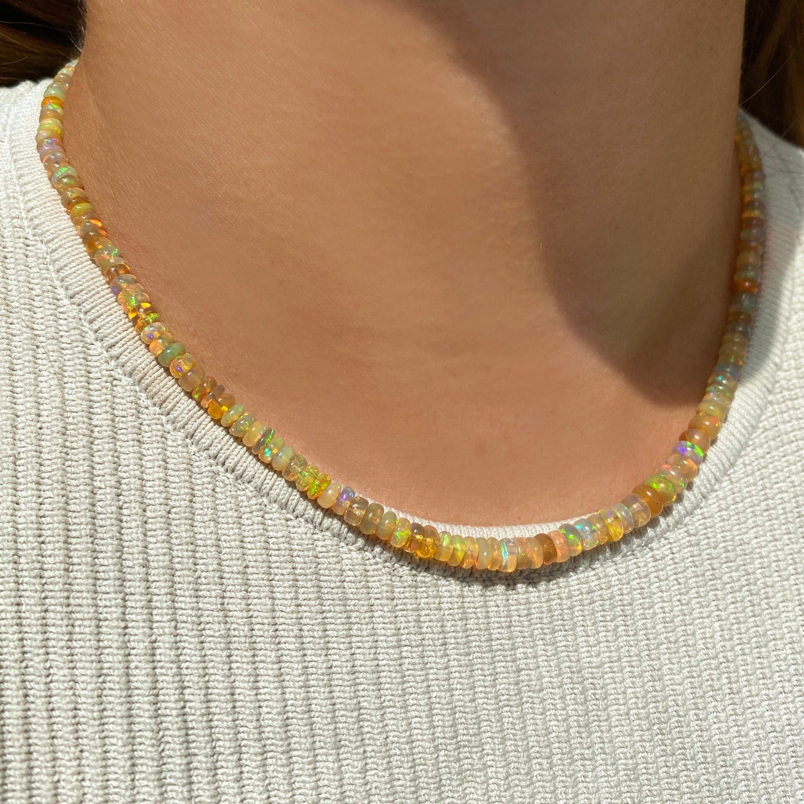 Shimmering beaded necklace made of faceted opals in shades of yellow, orange, and clear opals on a gold linking ovals clasp.