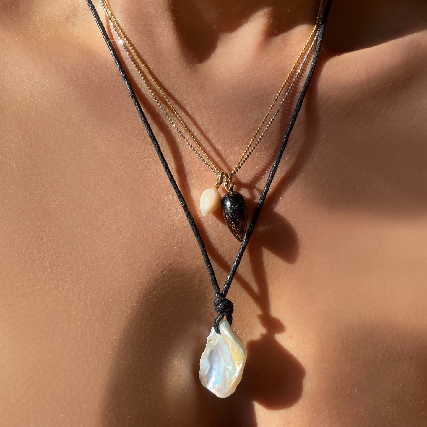 Keishi Pearl with Nylon Cord. Styled with two acorn charms hanging from a neck with two diamond cut bead chain necklaces.