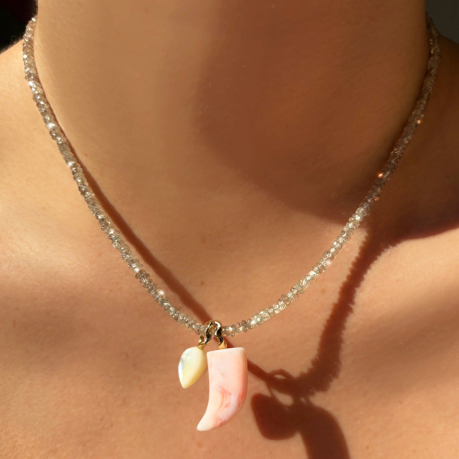 Pink opal horn charm. Styled on a neck with an acorn charm hanging from a beaded necklace.