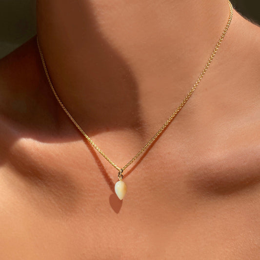 Mother of Pearl acorn drop charm. Styled on a neck hanging from a wheat chain necklace. 