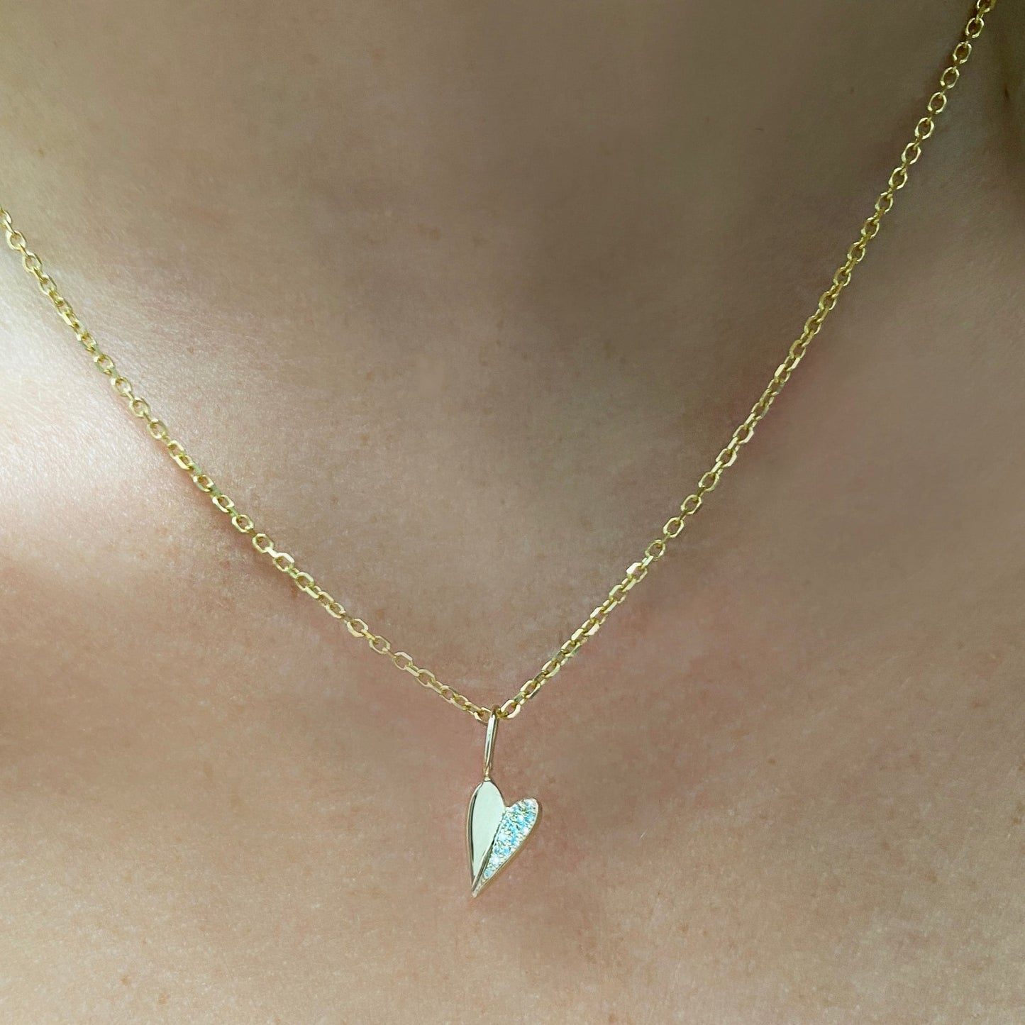 14k gold Diamond Cut Cable Chain Necklace. Styled on a neck with a folded pave heart charm