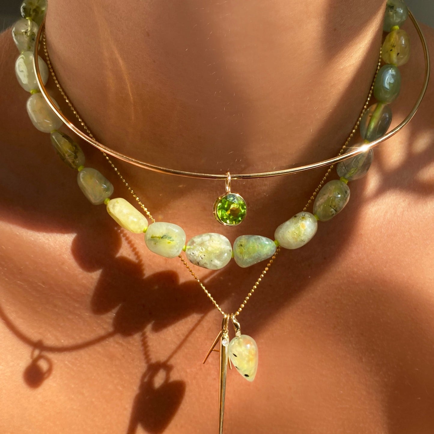 14k gold Peridot Round Solitaire Charm. Styled on a neck hanging from a wire choker necklace.