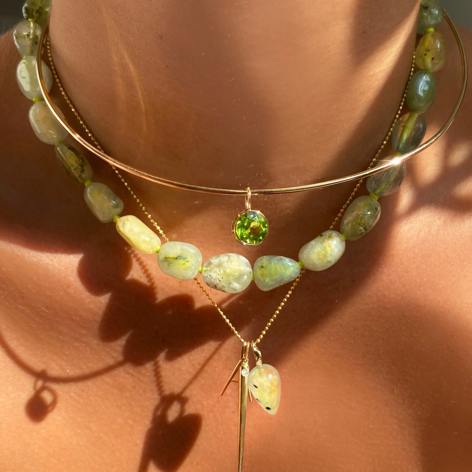 14k gold Peridot Round Solitaire Charm. Styled on a neck hanging from a wire choker necklace.