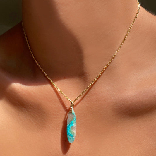 Chrysocolla in Quartz Surfboard Charm. Styled on a neck hanging from a wheat chain necklace. 
