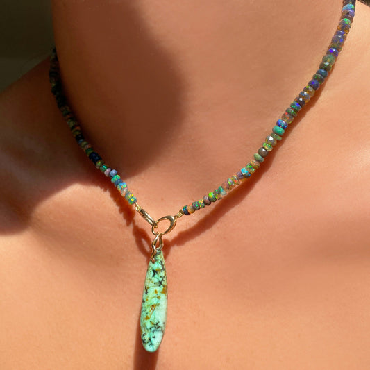 African Turquoise Surfboard Charm. Styled on a neck hanging from oval clasps of a beaded necklace.