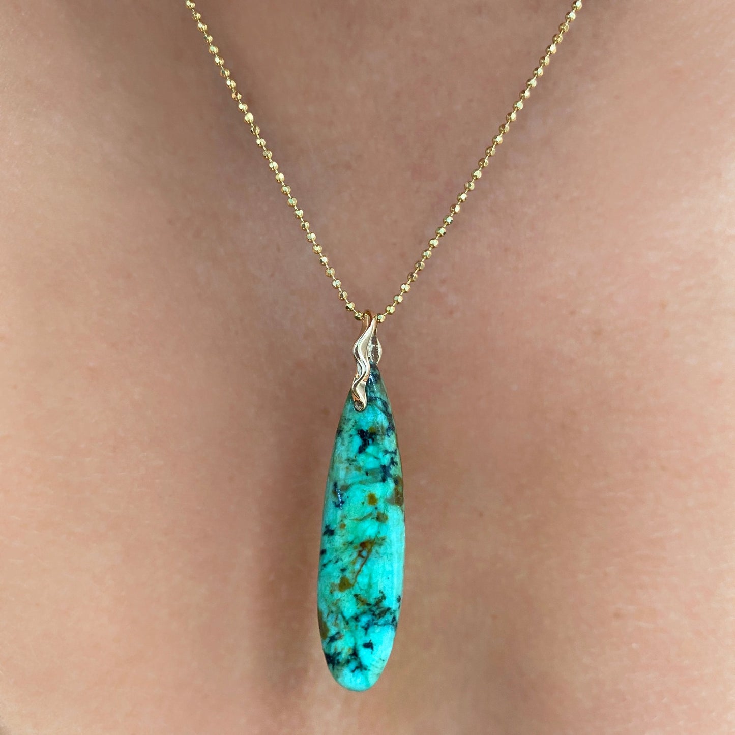 African Turquoise Surfboard Charm. Styled on a neck hanging from a diamond cut chain necklace.
