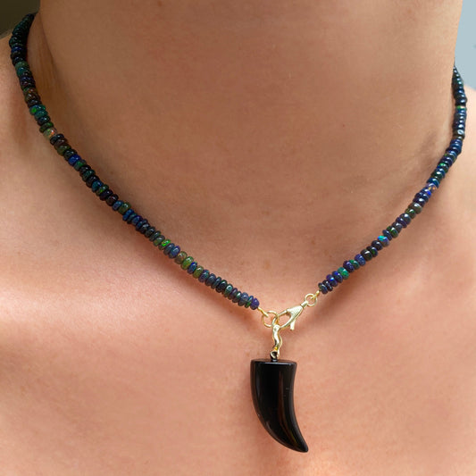 Black agate horn charm. Styled on a neck hanging from the lobster clasp of a beaded necklace.