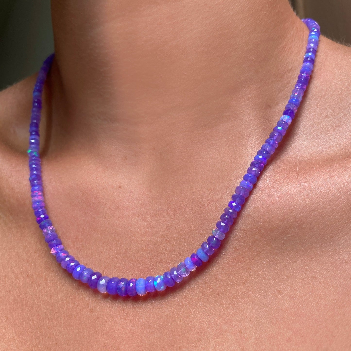 Shimmering beaded necklace made of faceted opals in shades of violet purple on a gold linking ovals clasp.