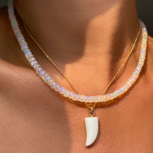 White agate horn charm. Styled on a neck hanging from a diamond cut bead chain necklace. 