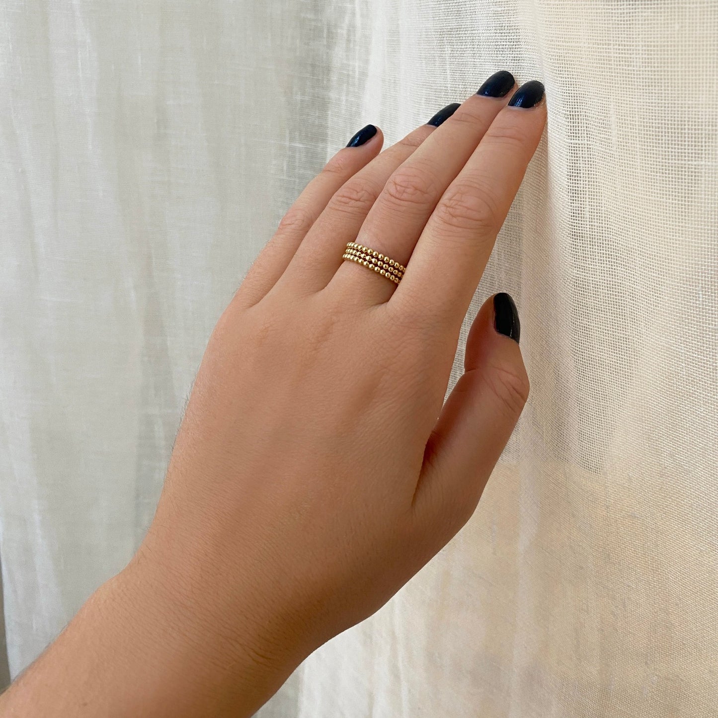14k gold bead rings styled on a hand