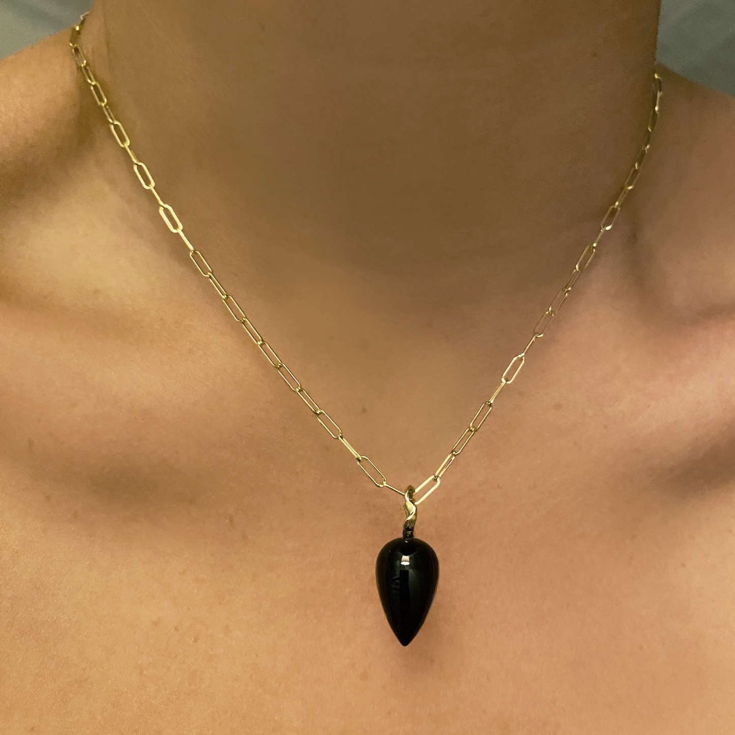 Black agate acorn drop charm. Styled on a neck hanging from a paperclip chain necklace