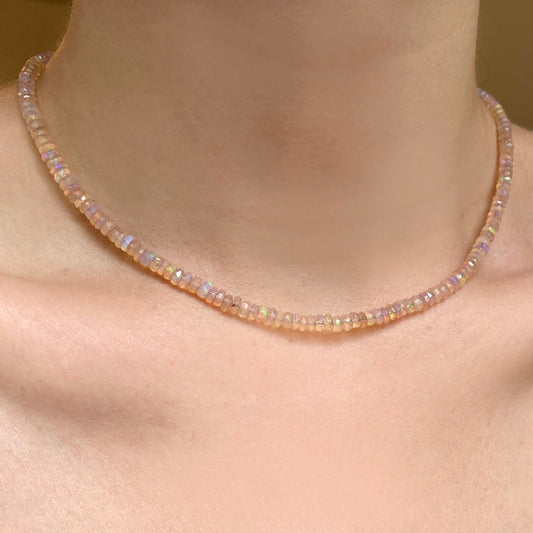 Shimmering beaded necklace made of faceted opals in shades of clear-light pink on a gold linking ovals clasp.