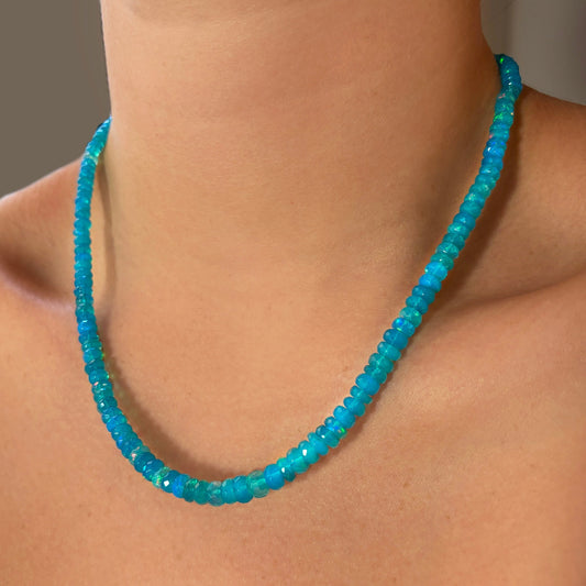 Shimmering beaded necklace made of faceted opals in shades of bright light blue on a gold linking ovals clasp. 