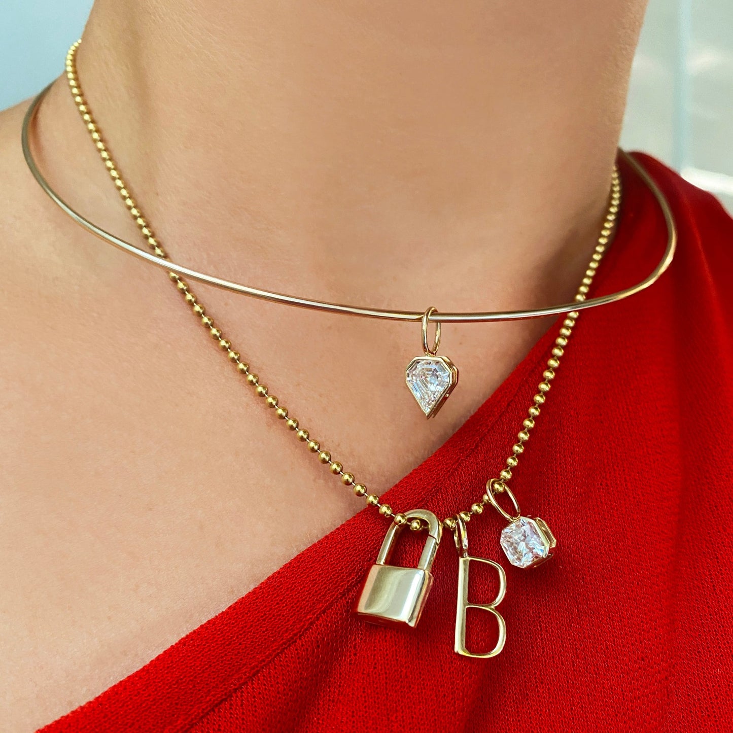 14k gold Aquila Cut Diamond Solitaire Charm. Styled on a neck with a padlock and B letter charm hanging from a bead chain necklace.