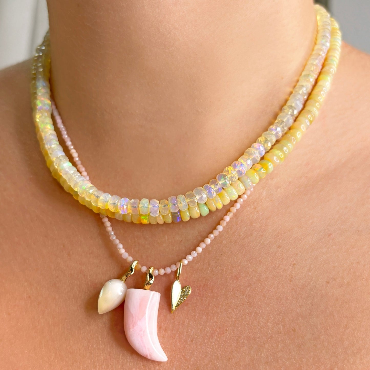 Mother of Pearl acorn drop charm. Styled on a neck with a horn and folded heart charms hanging from a beaded necklace.