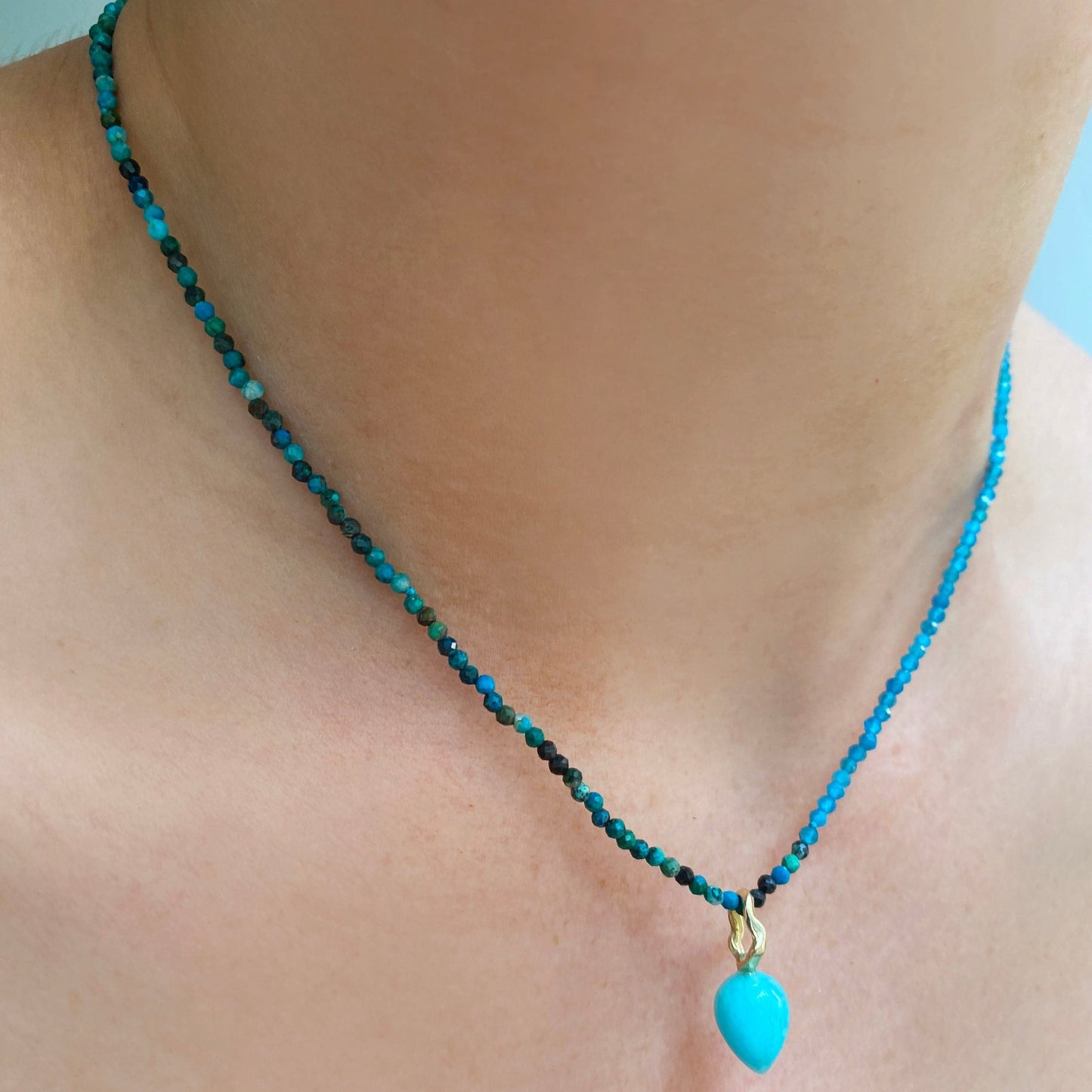 Amazonite acorn drop charm. Styled on a neck hanging from a beaded necklace.