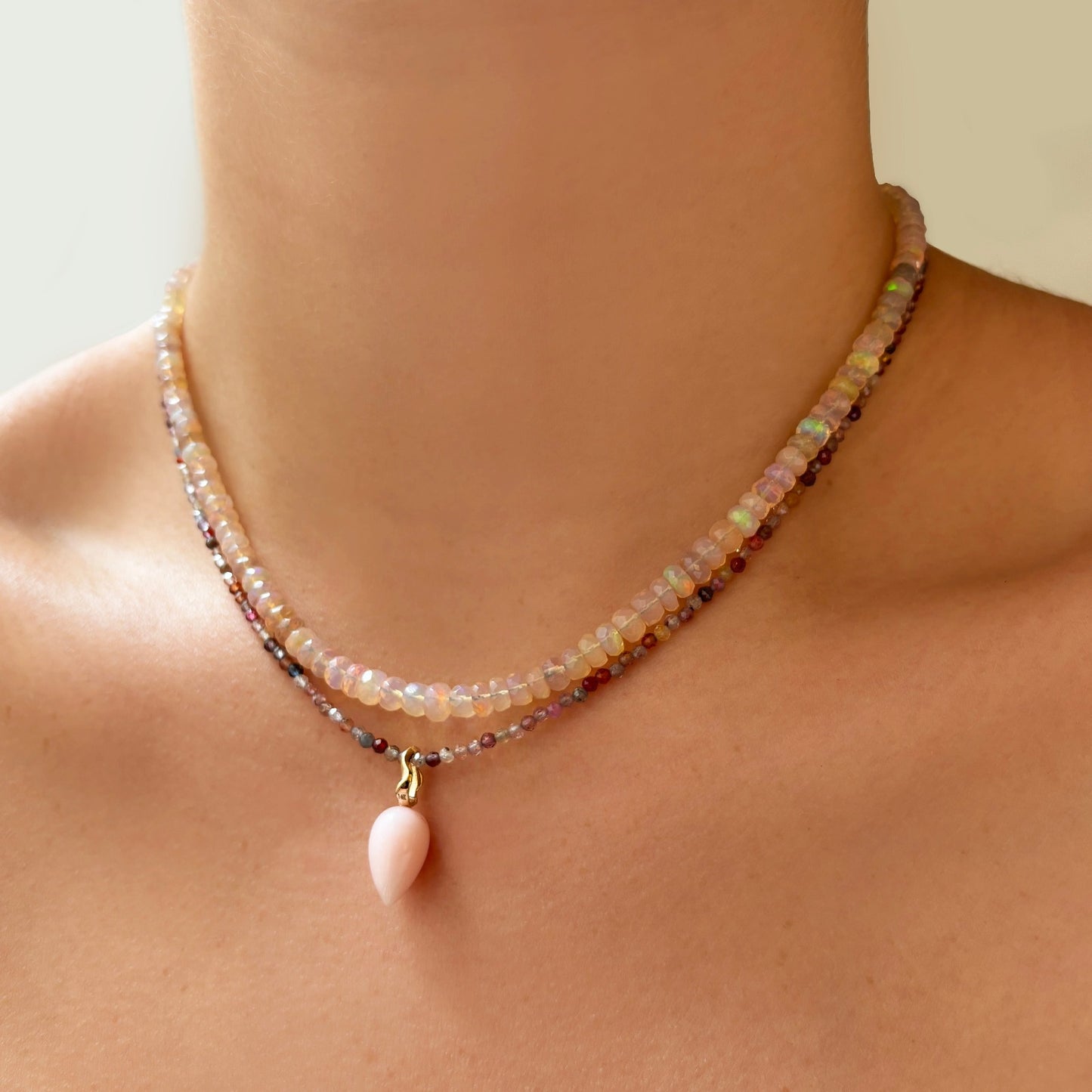 Peruvian pink opal acorn drop charm. Styled on a neck hanging from a beaded necklace.