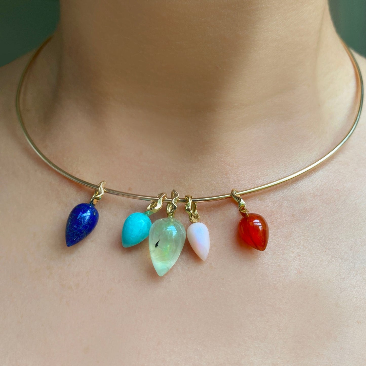5 acorn drop charms styled on a neck hanging from a wire choker necklace.