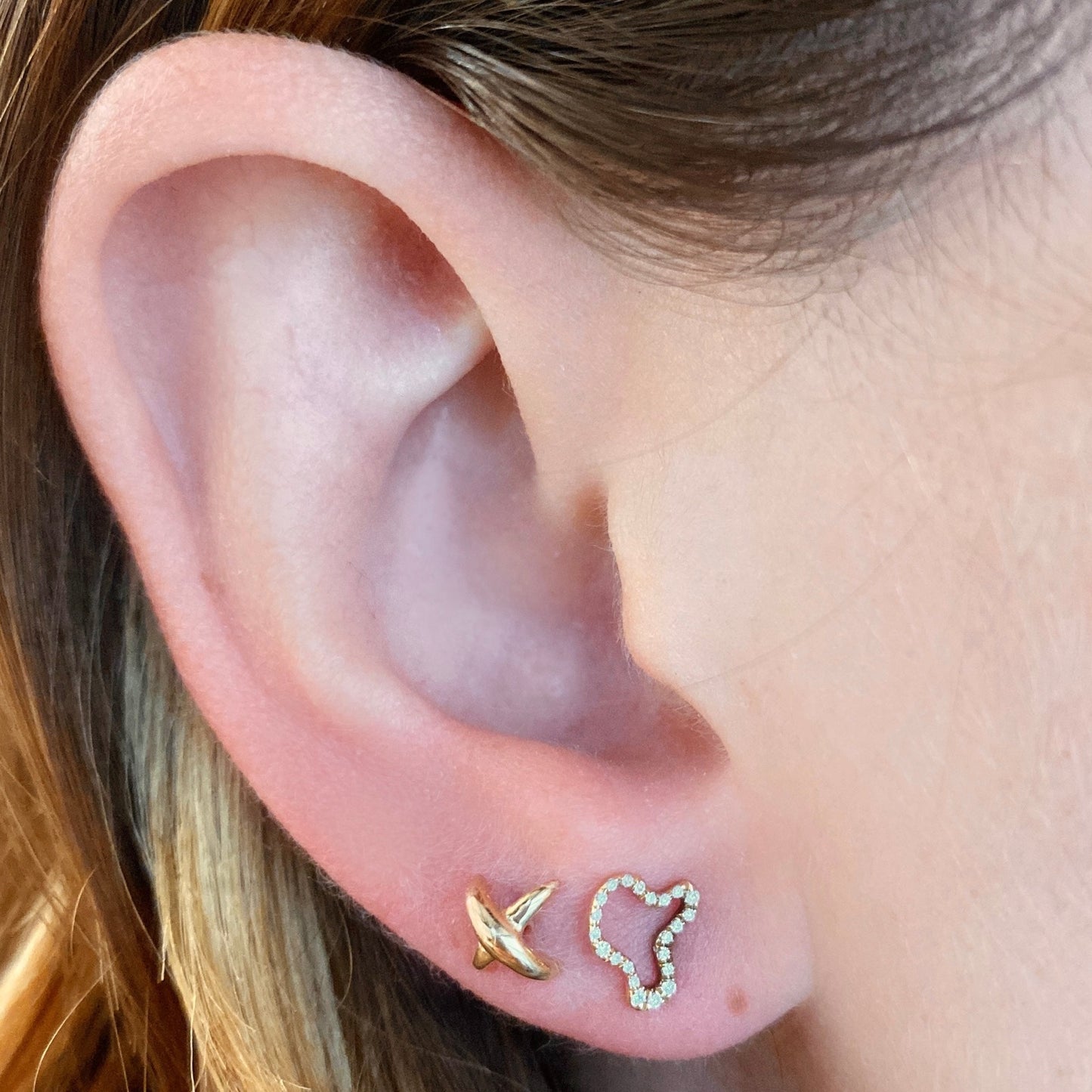 14k gold Stitch Stud Earrings styled on a ear with a full pave ripple stud earring