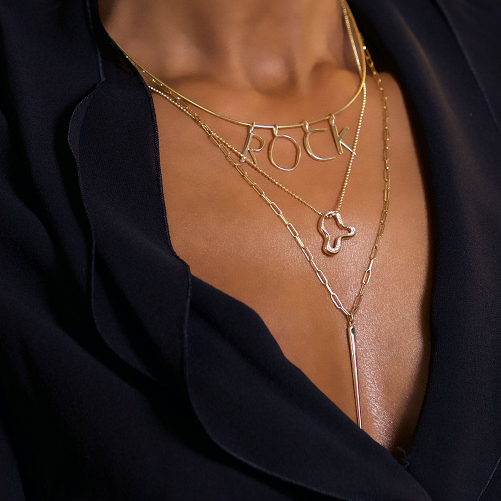 14K yellow gold R, O, C, and K letter charms styled on a neck layered with the wire choker necklace.