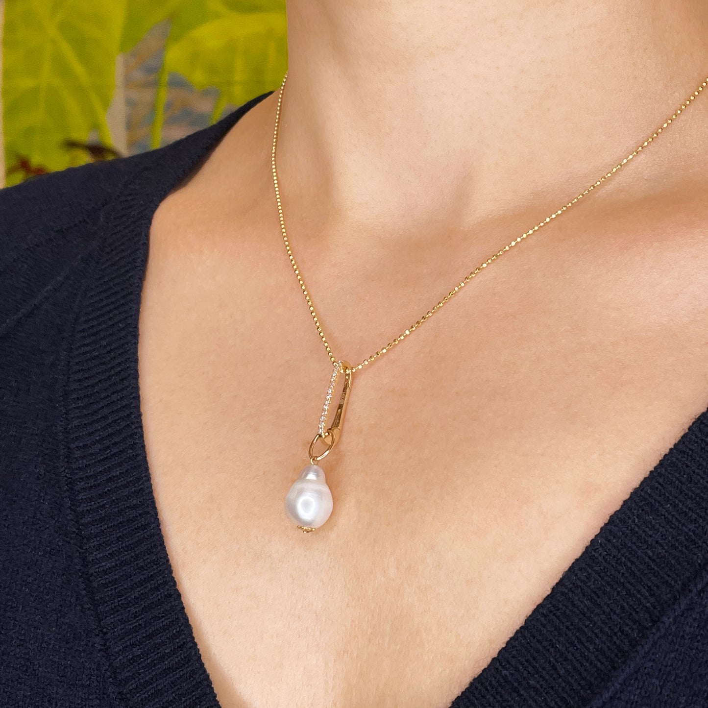 14k yellow gold oval push in charm with pave diamonds. Styled on a neck with a mini baroque pearl charm hanging from the diamond cut bead chain necklace. 