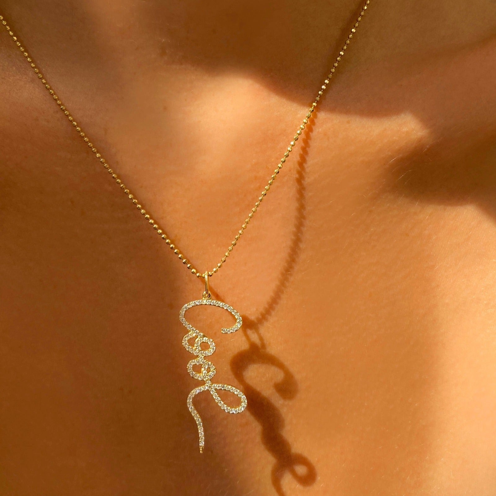 14k gold Pavé Graffiti 'Cool' Charm. Styled on a neck hanging from a diamond cut bead chain necklace