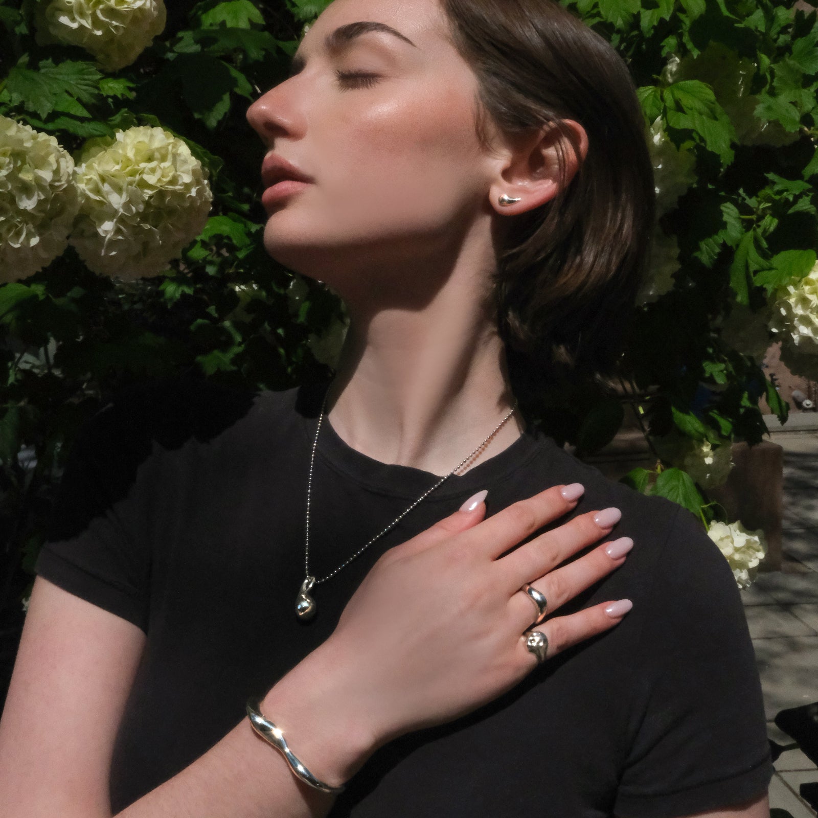 Model wearing sterling silver jewelry in front of a hydrangea bush in Brooklyn.