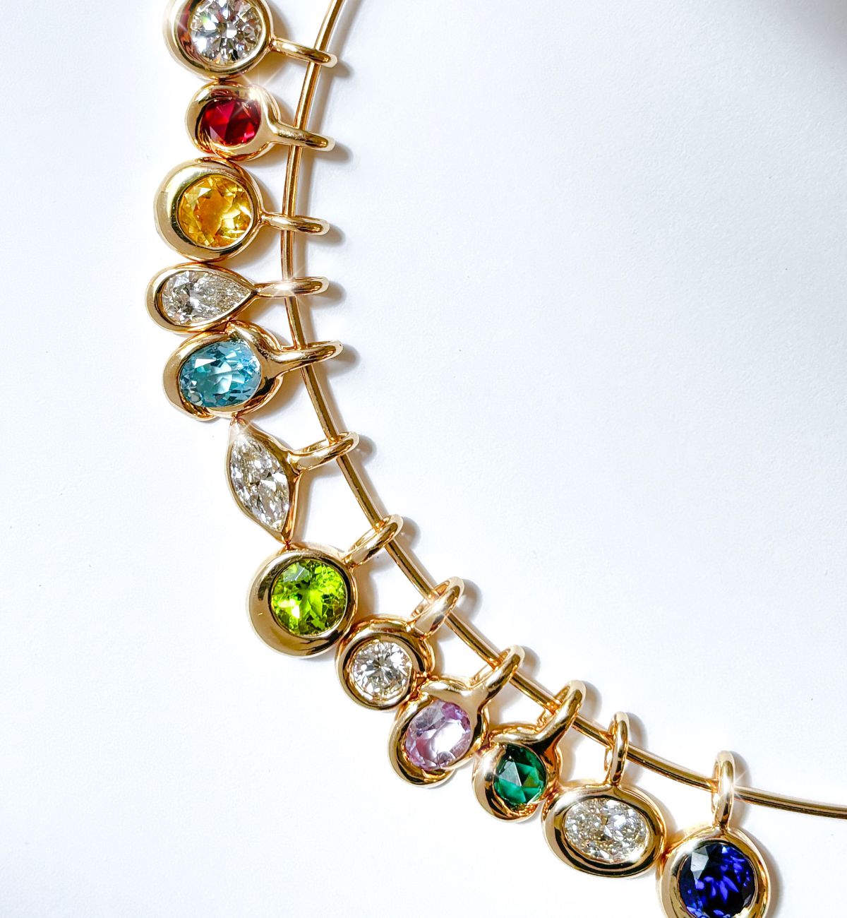 Layers of chunky gold chains and a pink opal slim gemstone necklace holding an assortment of gold and gemstone charms.