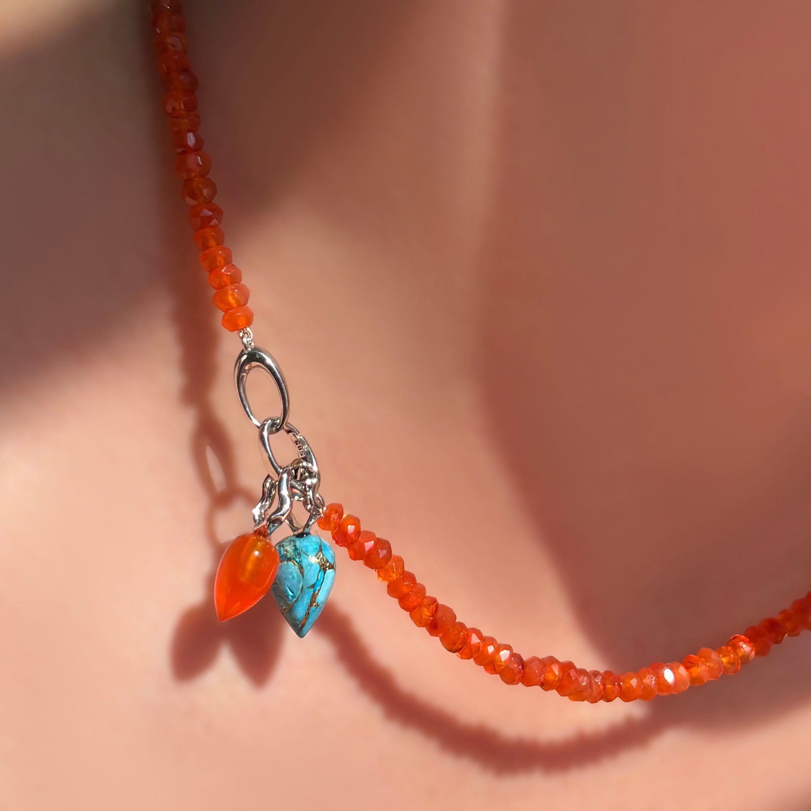 The AMANDA PEARL Faceted carnelian necklace with carnelian and turquoise drop charms strung on the linking ovals clasp in sterling silver. 