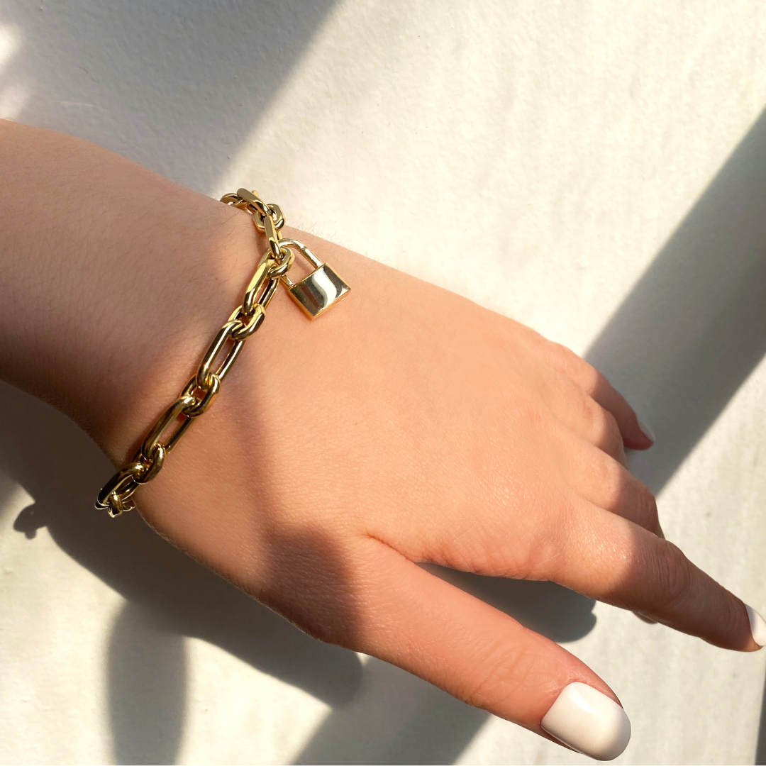 14k yellow gold padlock charm. Styled on a wrist locked onto a diamond cut link chain bracelet.