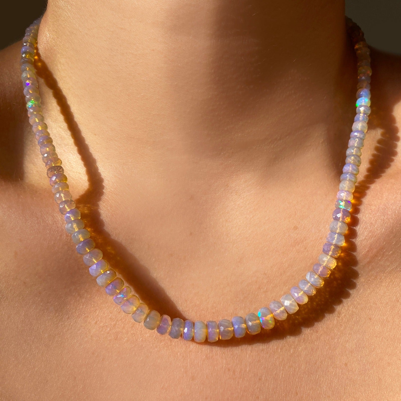 Shimmering beaded necklace made of faceted opals in shades of clear and light lilac on a gold linking ovals clasp. 