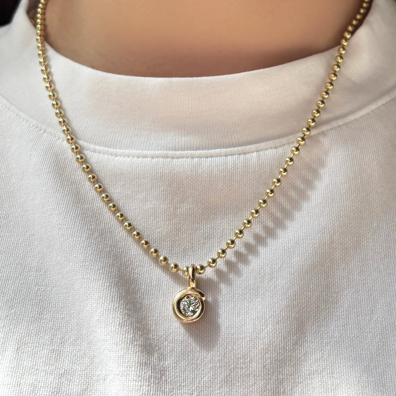 3mm bead chain with quill solitaire diamond bezel charm on a white tee.