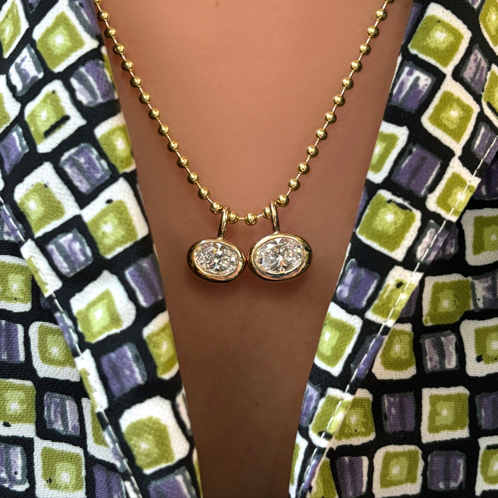 3mm bead chain with small and regular oval diamond molten solitaire charms on a model's neck.