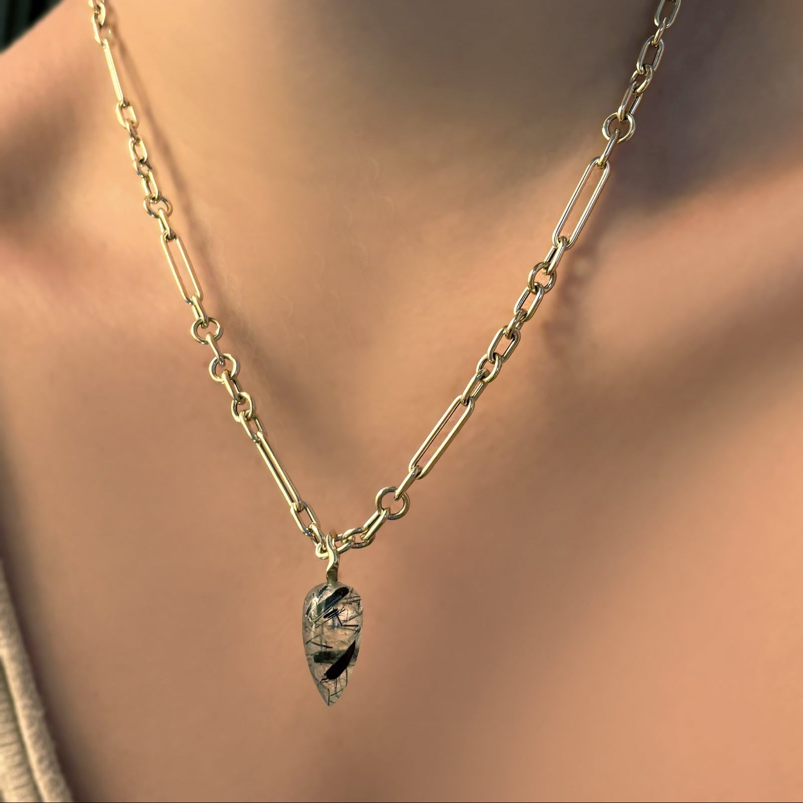 6mm irregular cable chain in yellow gold with a rutilated quartz gemstone drop charm on a model's neck.