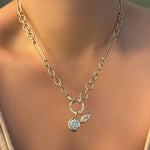 Chunky irregular cable chain with round pavé face charm lock dropping two molten solitaire charms on a model's neck.
