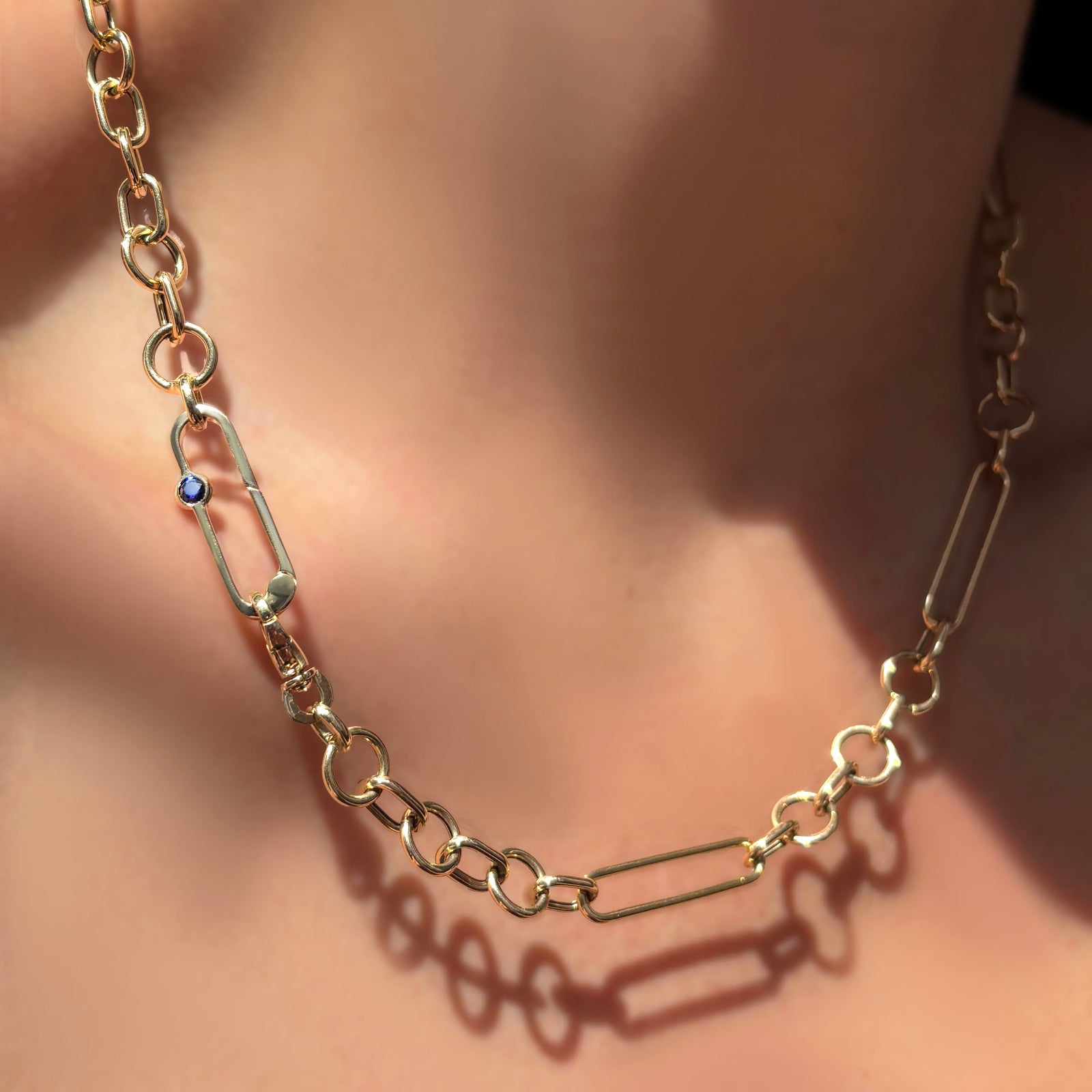 8mm irregular cable chain with a paperclip chain with sapphire attached in between the clasp on a model's neck.
