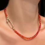 A blood orange faceted padparadscha sapphire necklace with 14k yellow gold molten safety pin charm lock.